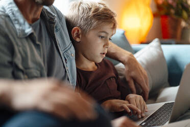 Boy using laptop sitting by parents at home - JOSEF08167