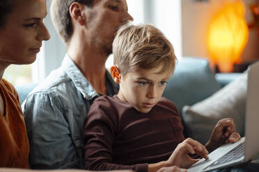 Blond boy using laptop sitting with parents at home - JOSEF08168