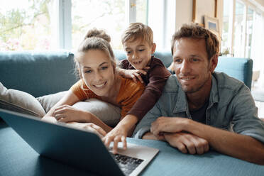 Happy family sharing laptop on sofa at home - JOSEF08171