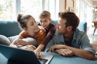 Smiling father and mother looking at son using laptop at home - JOSEF08172