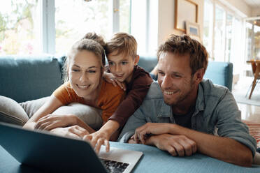 Happy mother and father with son watching video on laptop at home - JOSEF08173