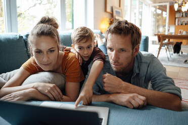 Boy with parents watching video on laptop in living room at home - JOSEF08175