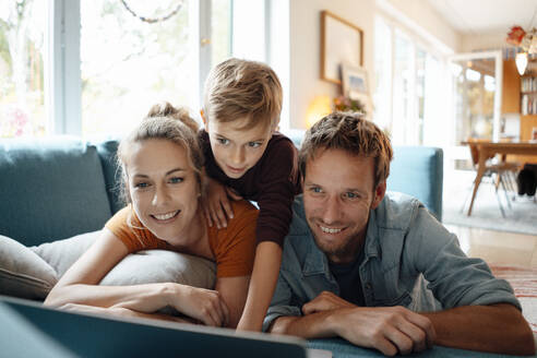 Glückliche Eltern mit Sohn, der zu Hause ein Video auf dem Laptop ansieht - JOSEF08176