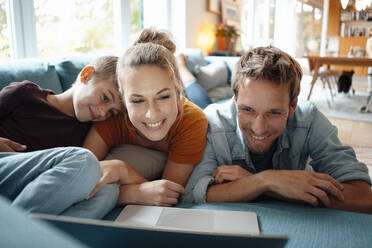 Smiling mother and father watching video with son through laptop in living room - JOSEF08177