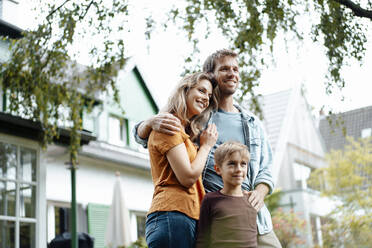 Smiling parents with son standing at backyard - JOSEF08226