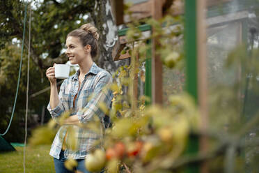 Lächelnde Frau mit Kaffeetasse im Hinterhof stehend - JOSEF08240