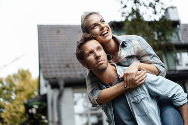 Man giving piggyback ride to happy girlfriend at backyard - JOSEF08247