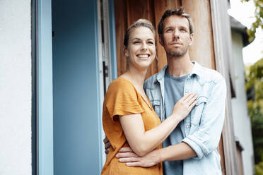 Happy woman with boyfriend standing at doorway - JOSEF08248