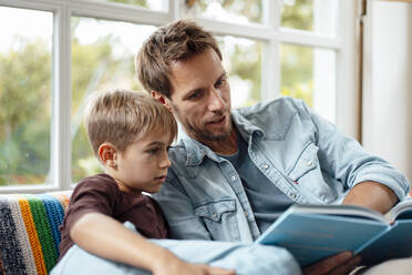 Father reading book to son at home - JOSEF08251