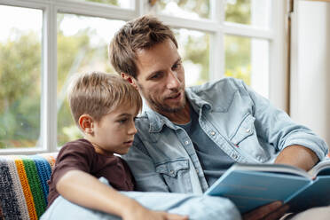Vater liest seinem Sohn zu Hause ein Buch vor - JOSEF08251