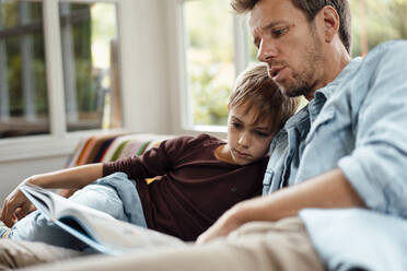 Man reading book to son at home - JOSEF08252