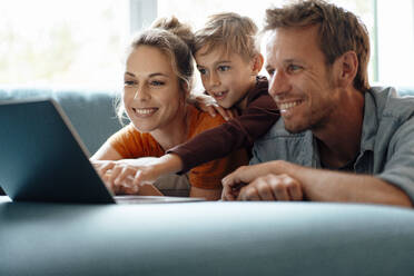 Happy parents with son watching video through laptop at home - JOSEF08265