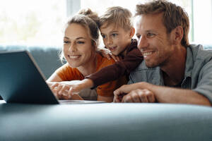 Glückliche Eltern mit Sohn, der zu Hause ein Video auf dem Laptop anschaut - JOSEF08265