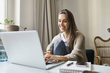 Smiling freelancer working on laptop at home - BSZF01995