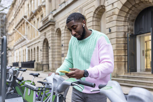 Mann scannt durch sein Smartphone und mietet ein Fahrrad an einer Parkstation - WPEF05886