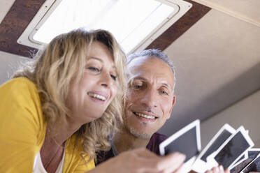 Smiling mature couple looking at photograph in camper van - EIF03515