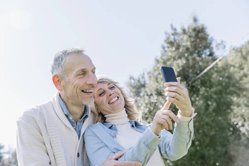 Fröhliches reifes Paar, das ein Selfie über ein Mobiltelefon macht - EIF03547