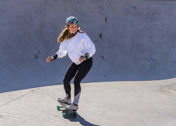 Young woman practicing skateboarding on pump track - STSF03153