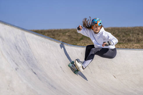 Junge Frau übt Skateboardfahren im Pumptrack an einem sonnigen Tag - STSF03154