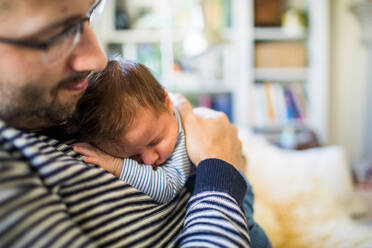 Ein Vater umarmt seinen neugeborenen Sohn zu Hause. - CAVF95823