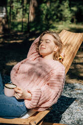 Frau mit Tasse Kaffee entspannt im Wald. - CAVF95830