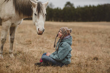 Teenager-Mädchen sitzt vor einem Pferd - CAVF95842