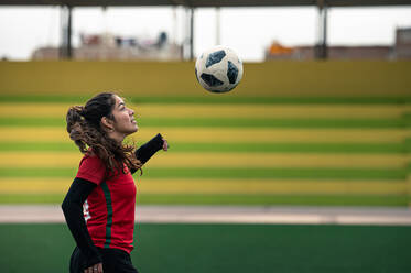Young female soccer player kicks the ball on the field - CAVF95902