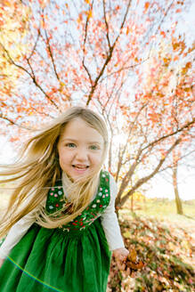 Closeup portrait of a young girl playing in the fall leaves - CAVF95918