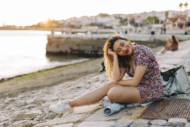 Smiling woman sitting at seashore - DCRF01071