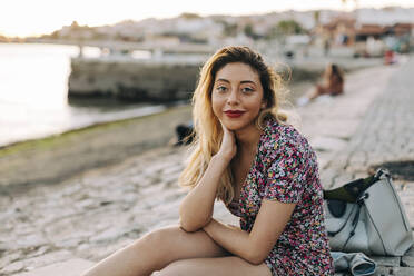 Young woman sitting at seashore - DCRF01072