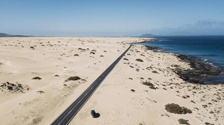 Spanien, Fuerteventura, Luftaufnahme einer Autobahn, die sich durch die sandige Landschaft des Naturparks Corralejo zieht - SIPF02818