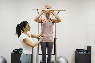 Fitness-Trainerin hilft einer Frau beim Pilates im Studio - DMGF00681