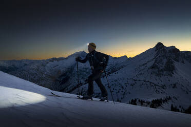 Mann mit Stirnlampe geht auf verschneitem Berg - MALF00392