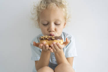 Blond girl with eyes closed kissing doughnut - SVKF00049