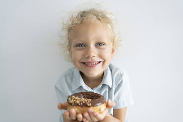 Smiling blond girl holding doughnut - SVKF00050