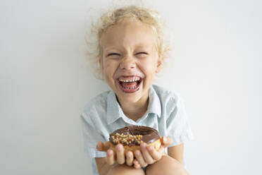 Cheerful girl holding doughnut and laughing - SVKF00052