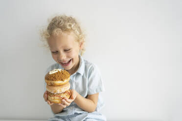 Glückliches Mädchen hält einen Stapel Donuts - SVKF00055