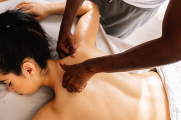Hands of african american professional therapist giving back massage - CAVF95939