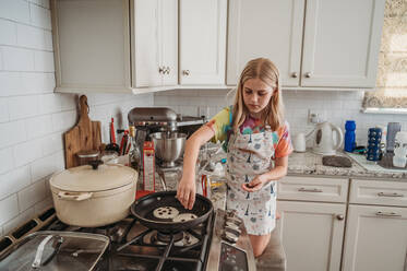 Young girl making chocolate chip pancakes - CAVF95954