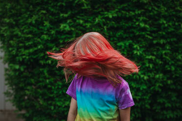 Young girl shaking head with dyed red hair outside - CAVF95956