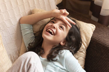 Girl laughing lying on the couch at home, Toledo, Spain - CAVF95960