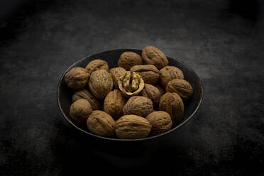 Studio shot of bowl of walnuts lying against black background - LVF09210