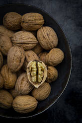 Studio shot of bowl of walnuts lying against black background - LVF09214