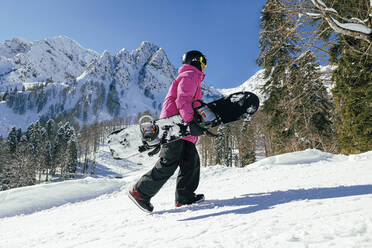 Mann mit Snowboard auf Schnee im Winter - OMIF00749