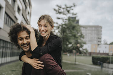 Happy young man giving piggyback ride to woman - MFF08939