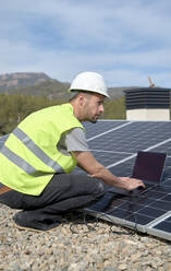 Ingenieur mit Laptop bei Sonnenkollektoren an einem sonnigen Tag - VEGF05551