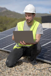 Ingenieur mit Laptop bei der Installation von Sonnenkollektoren an einem sonnigen Tag - VEGF05552