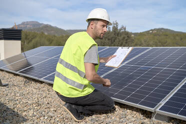 Ingenieur mit Bauplan vor Sonnenkollektoren an einem sonnigen Tag - VEGF05567