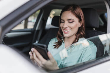 Glückliche Geschäftsfrau benutzt Smartphone im Auto - JRVF02920