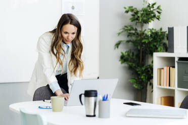 Businesswoman using laptop at desk in office - GIOF14949